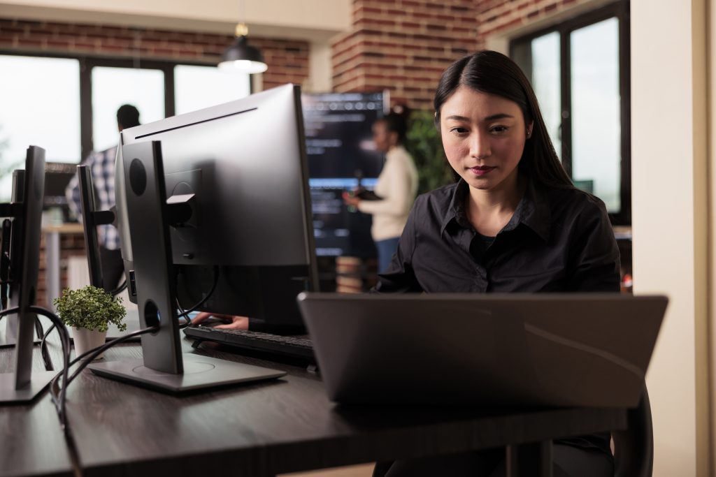 Vietnamese software developer working at an IT outsourcing company in Vietnam, coding in a modern office environment.