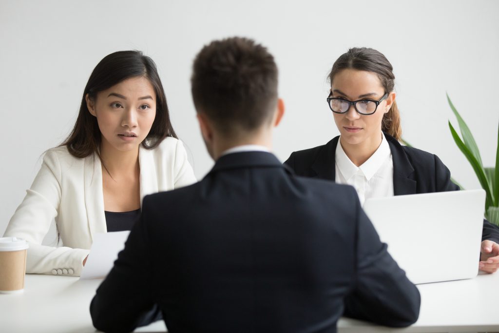 Diverse HR team remotely interviewing a male applicant to hire remote developers for their tech team.